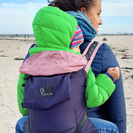 Shanek Inhaberin von Leolin mit Kind in Babytrage Mini Blue Purple Powder Melange am Meer