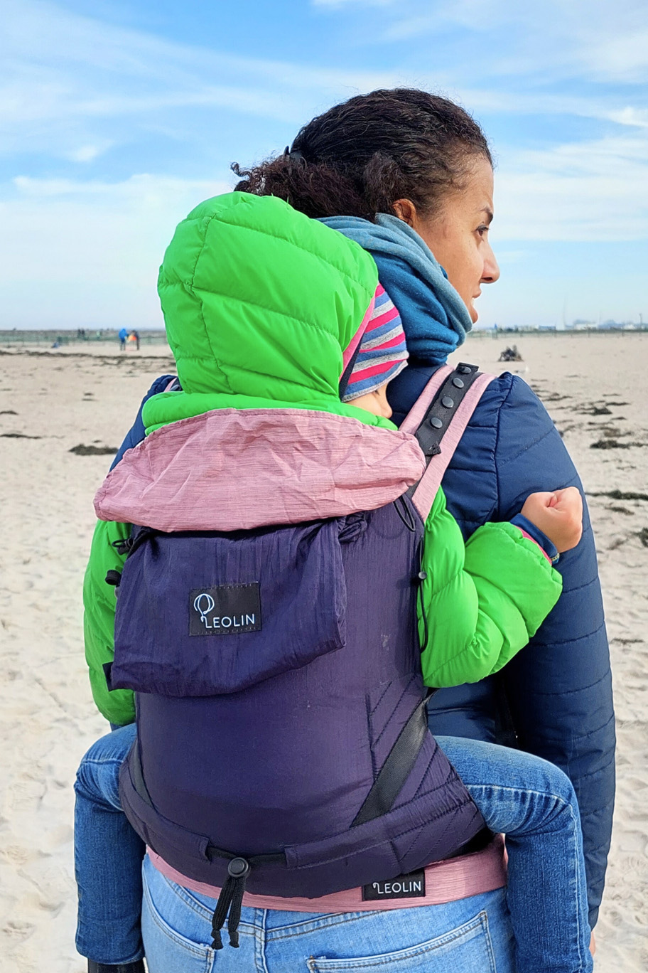 Shanek Inhaberin von Leolin mit Kind in Babytrage Mini Blue Purple Powder Melange am Meer